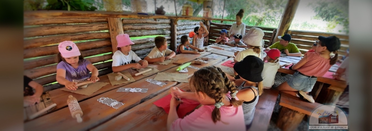 Grupa dzieci siedzi przy stole robiąc prace z plasteliny