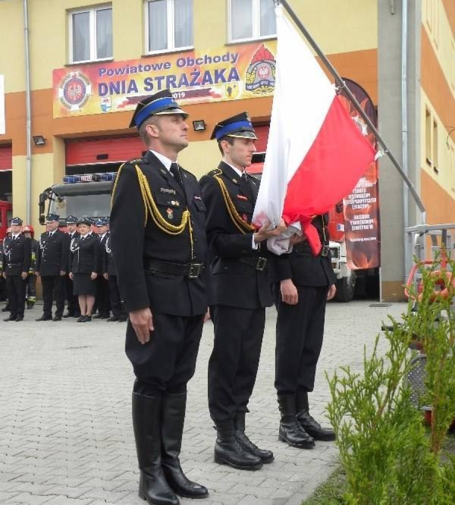 Troje strażaków trzyma flagę Polski 