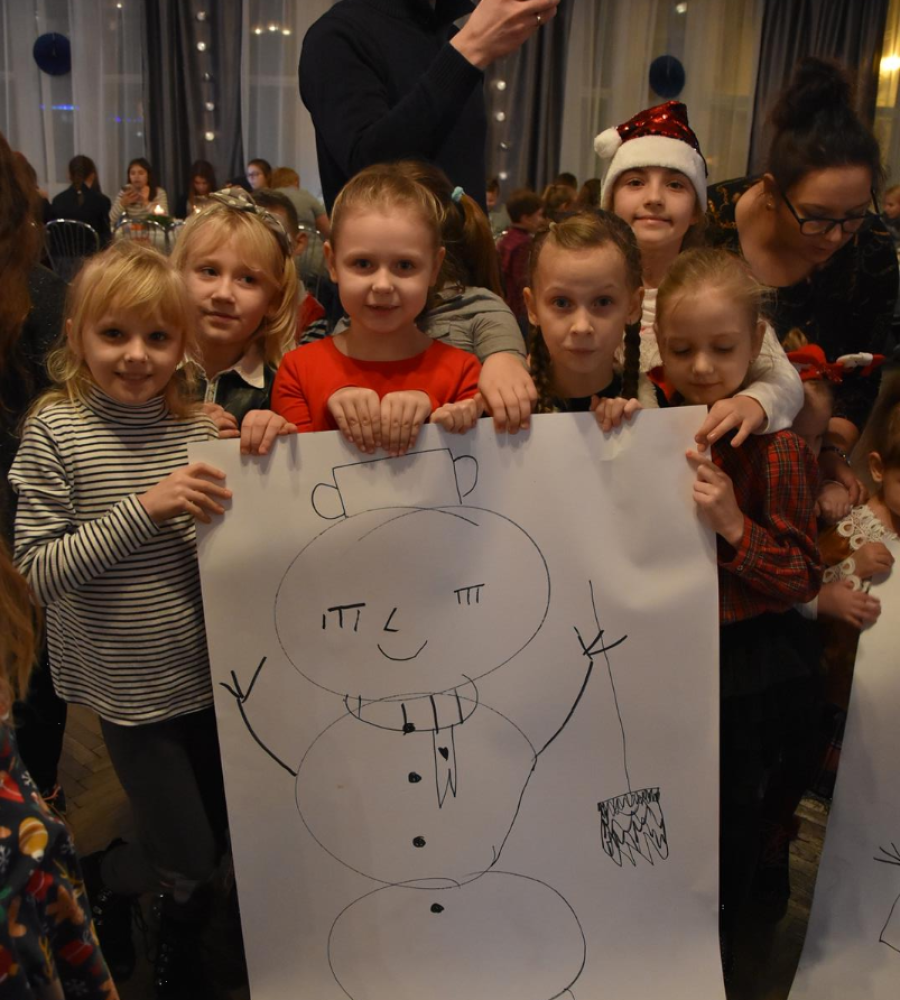 siedmioro dzieci przedstawiają narysowanego przeze nie bałwanka