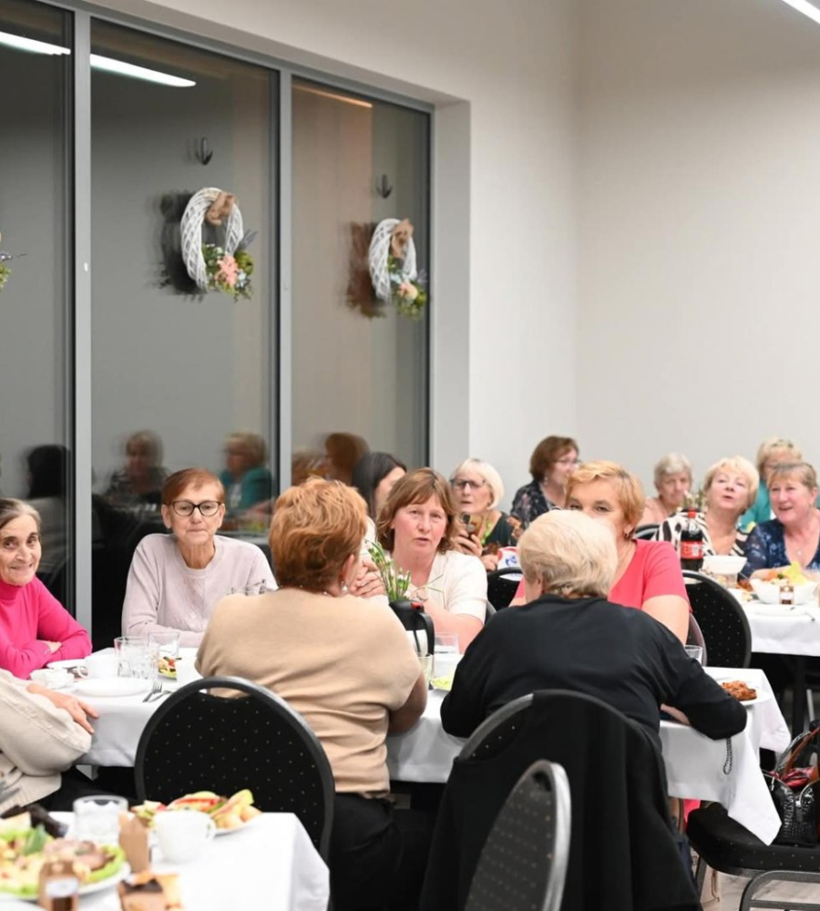 Goście siedzący przy stołach podczas wydarzenia Gminny Dzień Seniora