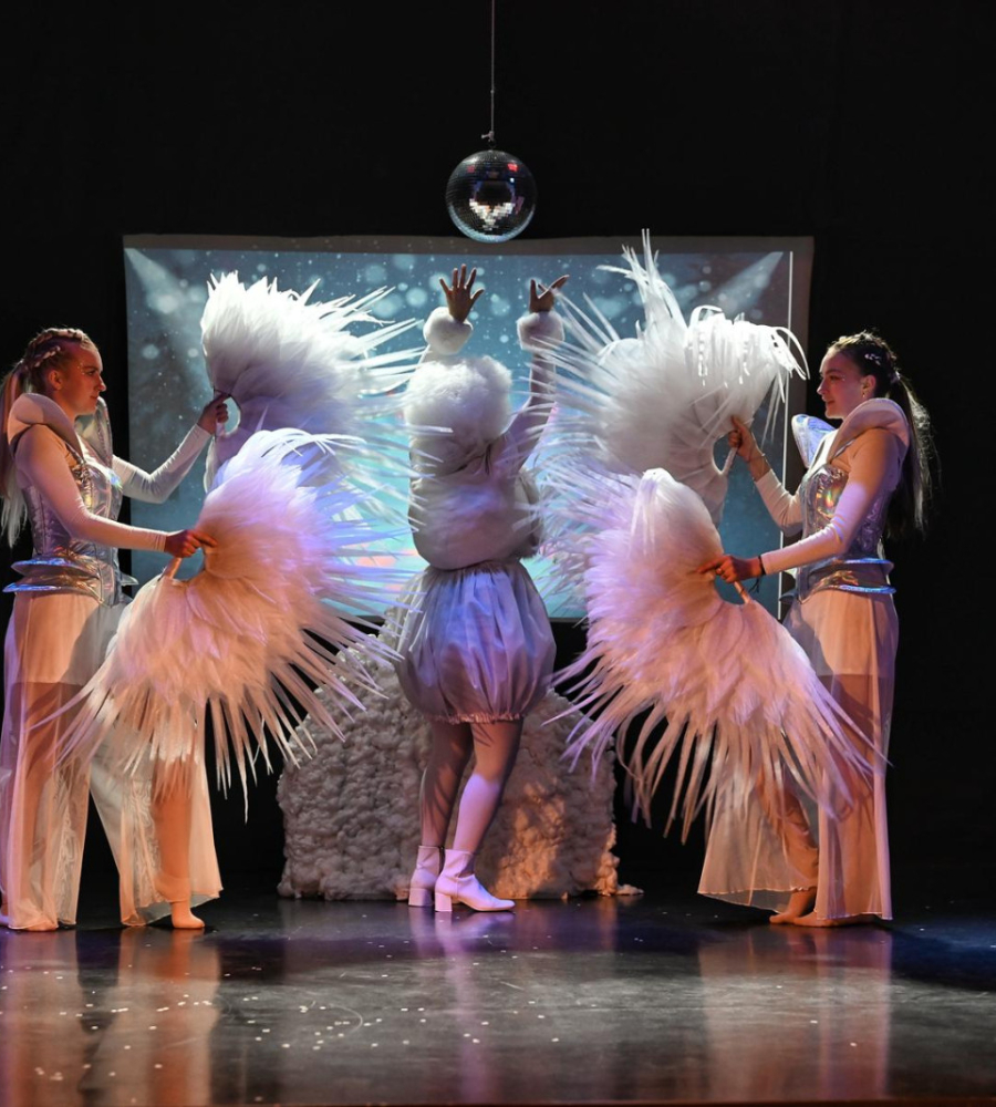 Na scenie tańczą trzy osoby w zimowej scenerii